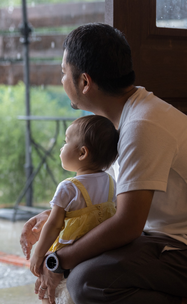 Dad and daughter looking out at rainy garden